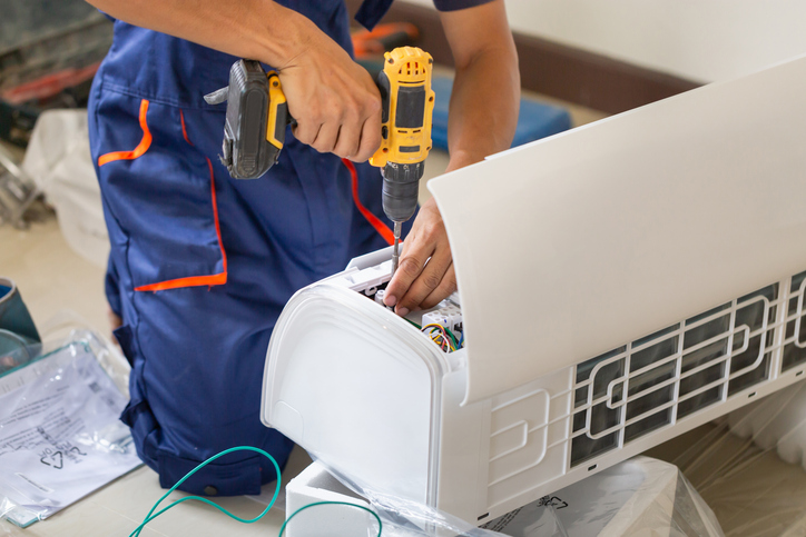 Young repairman fixing air conditioner unit, Maintenance and repairing concepts