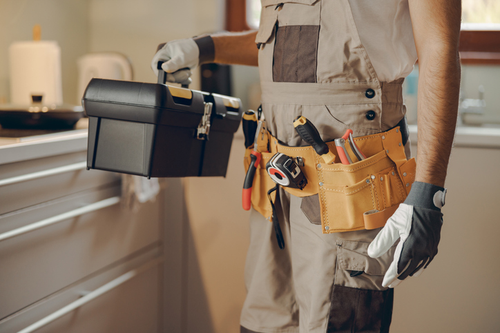 Close up of professional handyman standing on home kitchen and holding his tool bag