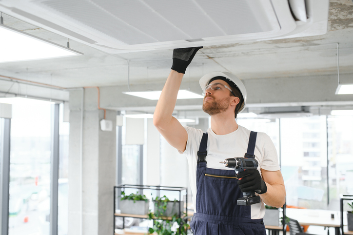 happy male technician repairing air conditioner