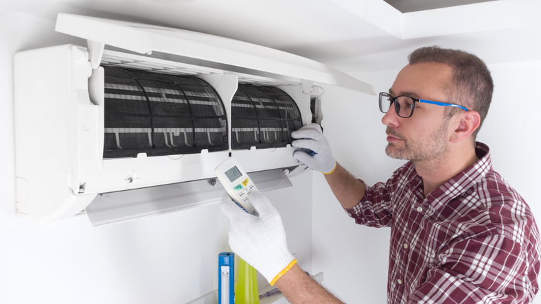 Service guy cleaning and maintaining air condition unit.