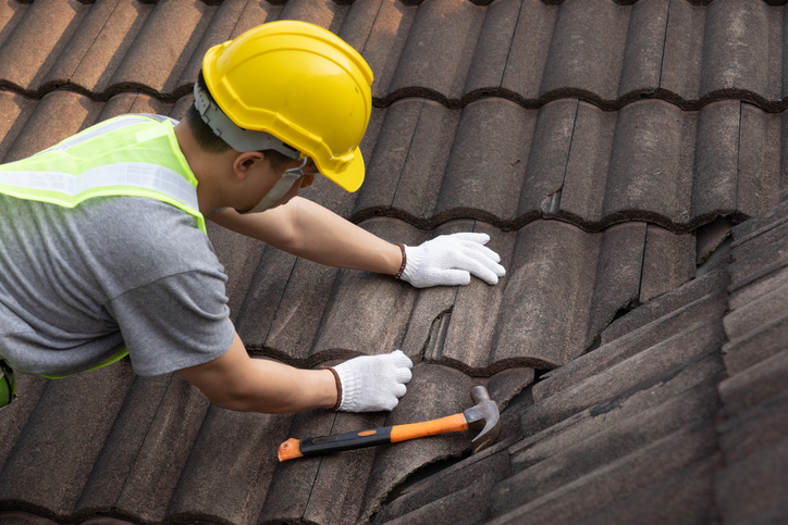 Worker man replace tile of the old roof