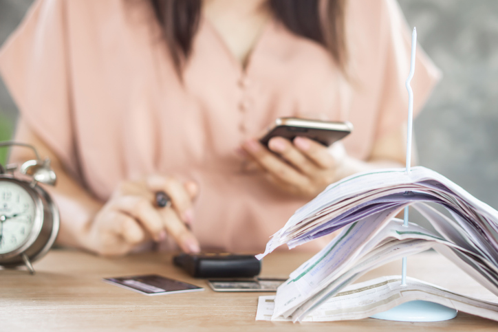 woman hand counting expenses with smart phone and credit cards,bills on desk