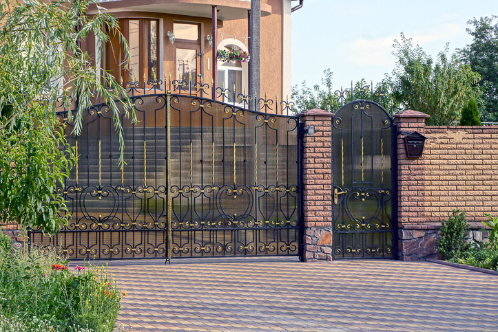 A large metal gate and a brown brick fence in the street stock photo