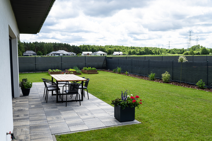 A modern table made of raw wood covered with yacht varnish, advantages of installing a privacy fence, standing on the garden terrace.