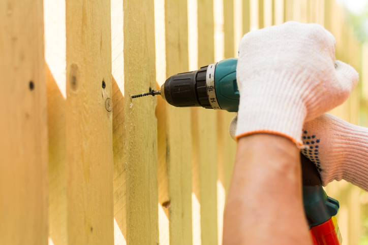 Hands of the carpenter holding electric screwdriver in work close up