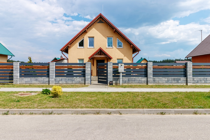 New small house against the blue sky with asphalt road and green grass.