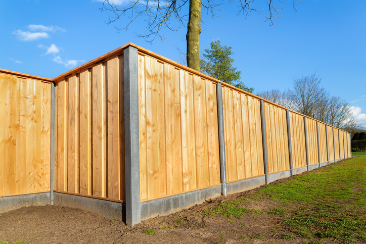 Outside new wooden fence, advantages of installing a privacy fence, around garden stock photo