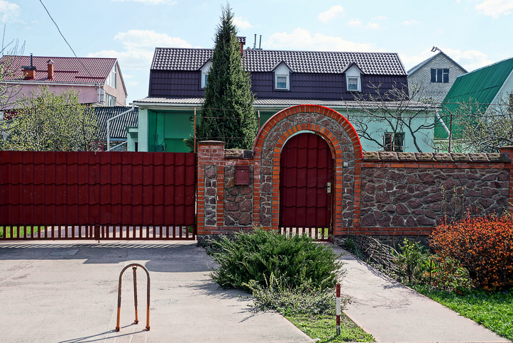 stone fence with a red door in the street with decorative green plants